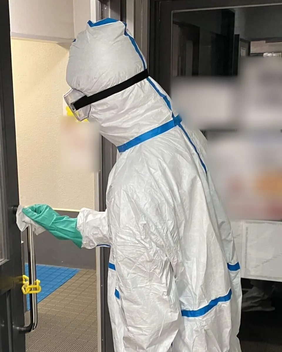防護服を着た当社スタッフが、建物の入口の扉を開けているところ